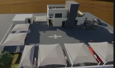 Aerial view of a charging station: the service building and a forecourt shaded by fabric canopies.